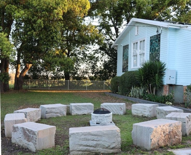 The yarning circle with fire pit in front of a classroom and treeline.