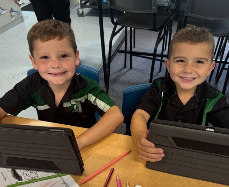 Two smiling students using ipads
