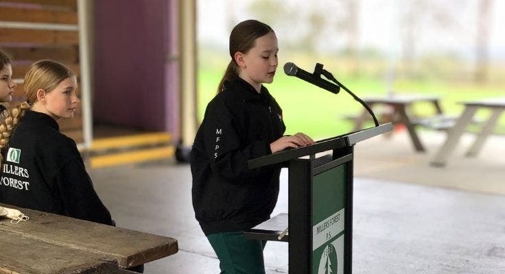 Student speaking at a podium, using a microphone.